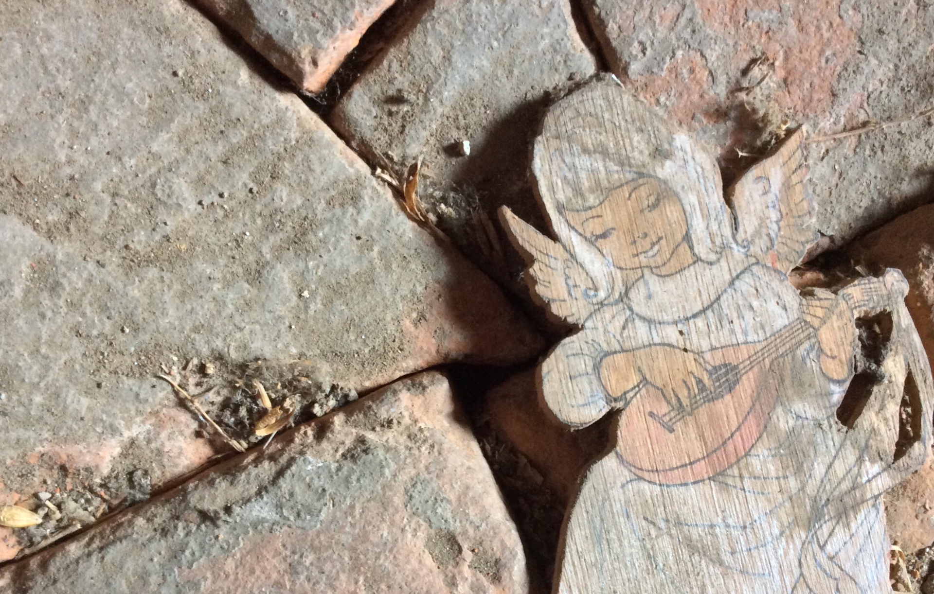 Paper angel illustration found resting on a weathered brick floor