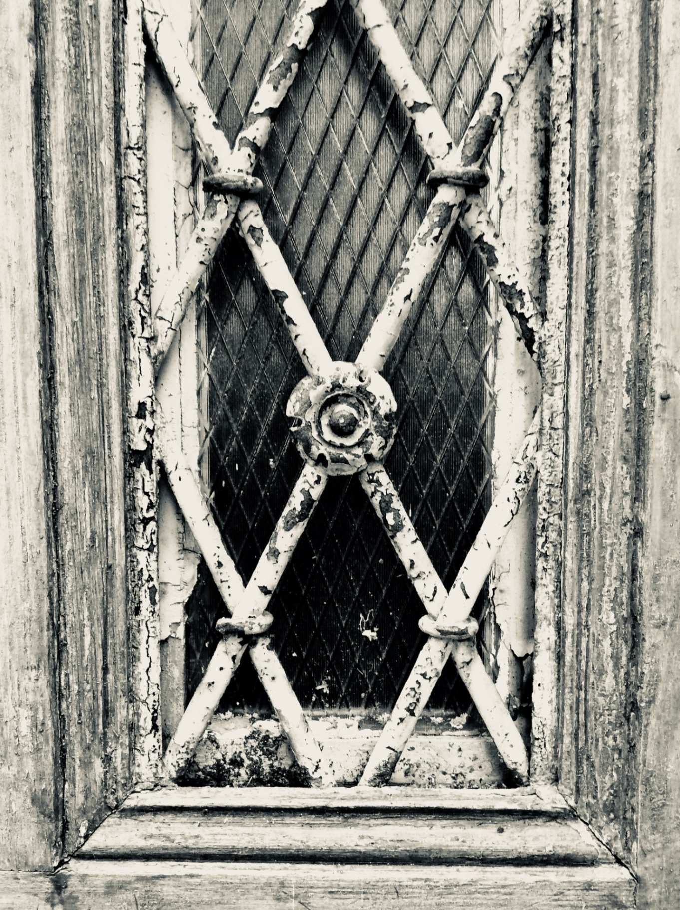 Weathered diamond-pattern window grille with peeling paint